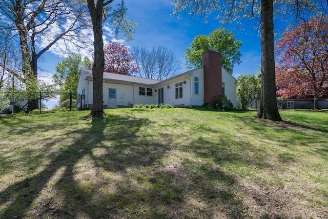 rear view of property with a yard, fence, and a chimney