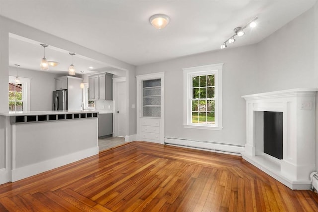 14 E Division St, Holbrook, MA 02343 - unfurnished living room with a baseboard radiator, a baseboard heating unit, healthy amount of natural light, and wood finished floors