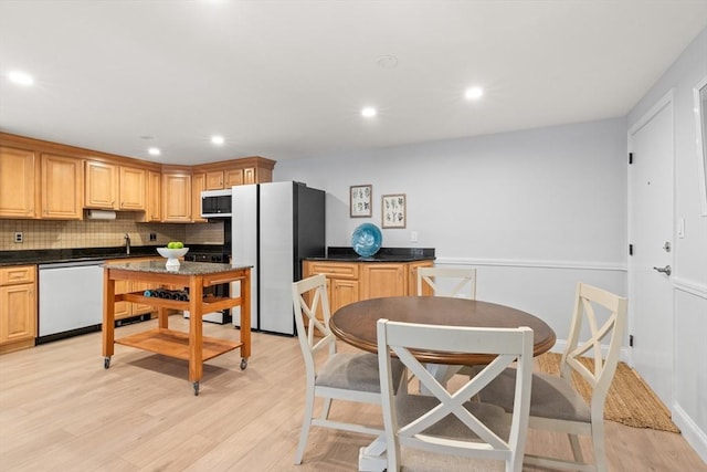 kitchen with decorative backsplash, white appliances, light hardwood / wood-style flooring, and light brown cabinets