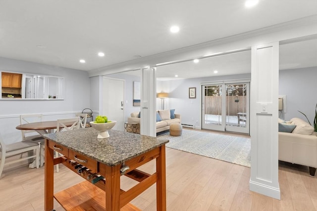 kitchen with a baseboard radiator, dark stone countertops, and light wood-type flooring