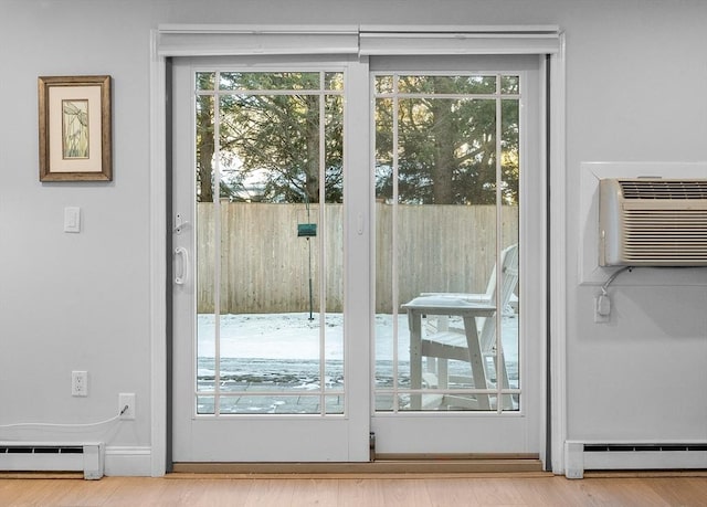 entryway with a wall unit AC, a healthy amount of sunlight, and baseboard heating