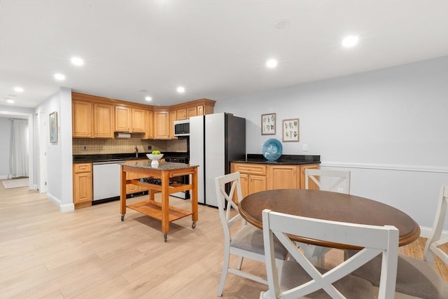 kitchen with sink, white appliances, light brown cabinetry, decorative backsplash, and light wood-type flooring