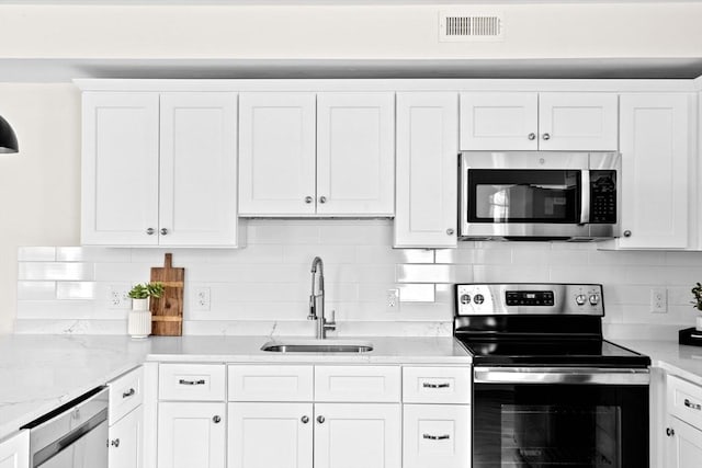 kitchen featuring appliances with stainless steel finishes, a sink, visible vents, and white cabinets