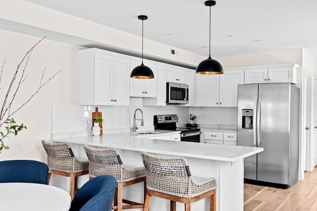 kitchen with a peninsula, appliances with stainless steel finishes, backsplash, and a sink