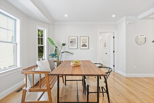 dining space featuring light wood-type flooring and crown molding