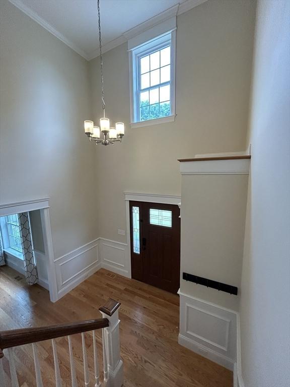 61 School St Unit B, Natick, MA 01760 - entryway with a chandelier, ornamental molding, wood finished floors, and wainscoting