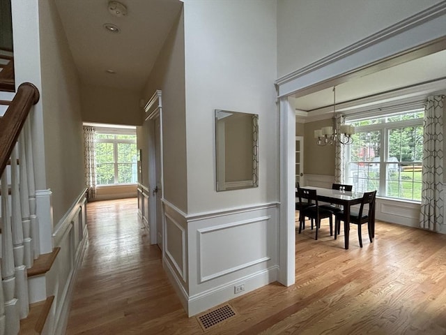 61 School St Unit B, Natick, MA 01760 - hall with a chandelier, wood finished floors, a decorative wall, wainscoting, and stairs