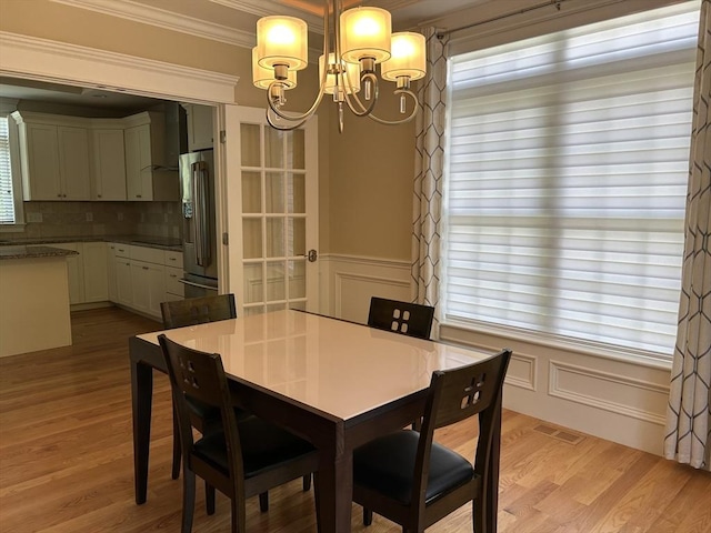 61 School St Unit B, Natick, MA 01760 - dining space with a chandelier, ornamental molding, a decorative wall, light wood-type flooring, and a wainscoted wall