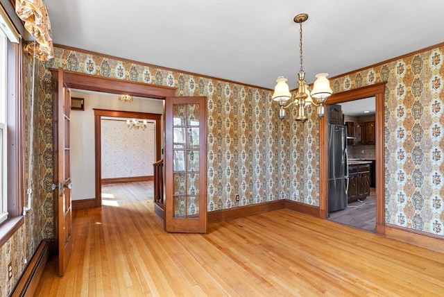 unfurnished dining area featuring baseboard heating, wallpapered walls, baseboards, a chandelier, and light wood-style floors