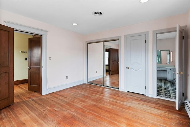 unfurnished bedroom featuring two closets, baseboards, and light wood-style floors