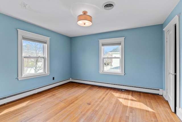 unfurnished bedroom with visible vents, hardwood / wood-style floors, baseboard heating, and multiple windows
