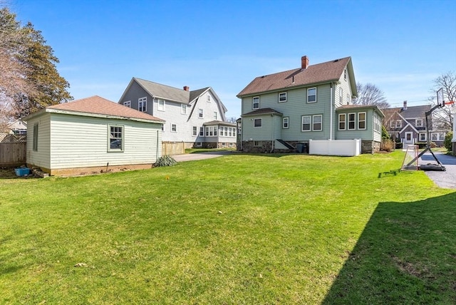 rear view of house featuring a yard, a chimney, and fence
