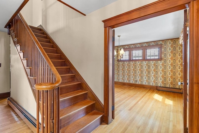 stairway with a baseboard radiator, hardwood / wood-style floors, and a chandelier
