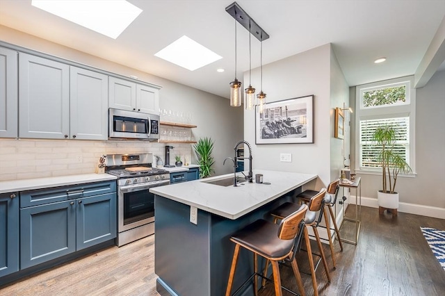 101 Draper St Unit 3, Boston, MA 02122 - kitchen with appliances with stainless steel finishes, a sink, a skylight, a breakfast bar, and light wood-style flooring