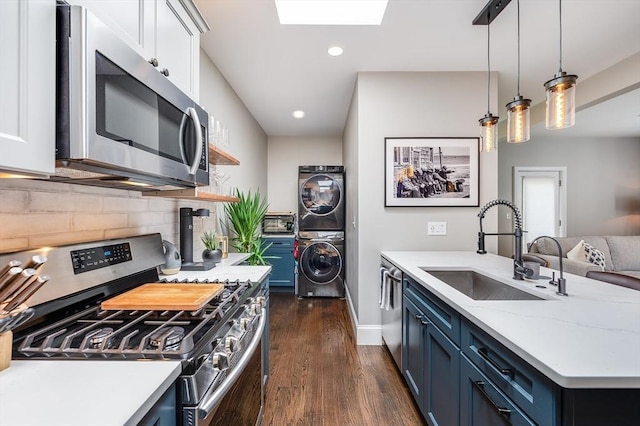 101 Draper St Unit 3, Boston, MA 02122 - kitchen with appliances with stainless steel finishes, a sink, estacked washer and dryer, dark wood-type flooring, and blue cabinets