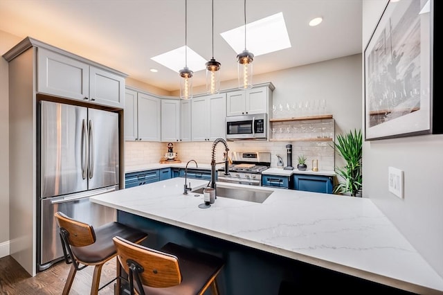 101 Draper St Unit 3, Boston, MA 02122 - kitchen featuring appliances with stainless steel finishes, a skylight, light stone counters, a breakfast bar, and tasteful backsplash