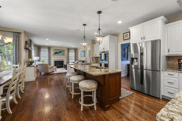 kitchen with white cabinetry, stainless steel appliances, dark wood-style floors, open floor plan, and light stone countertops