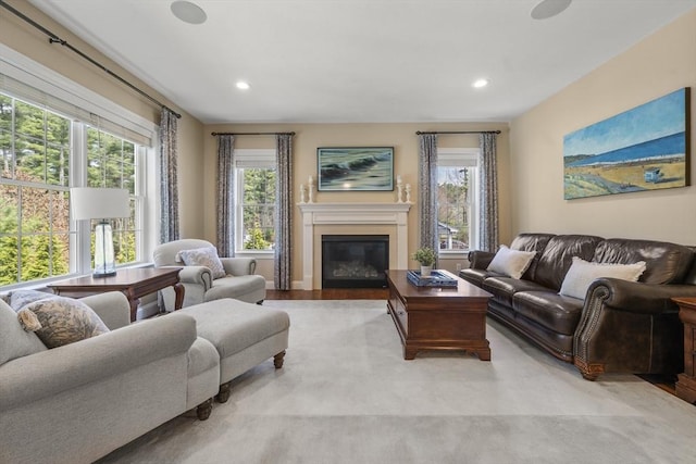 living room featuring recessed lighting, a glass covered fireplace, and plenty of natural light