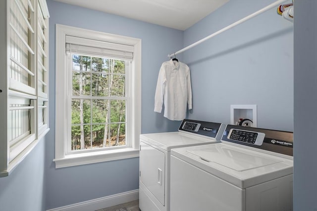 clothes washing area featuring a healthy amount of sunlight, separate washer and dryer, laundry area, and baseboards