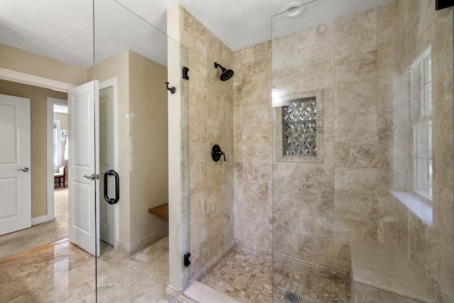 full bathroom featuring a tile shower and baseboards