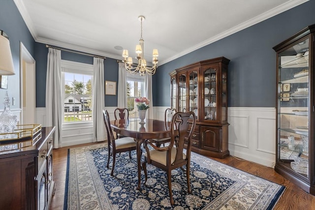 dining room featuring ornamental molding, an inviting chandelier, wainscoting, and wood finished floors
