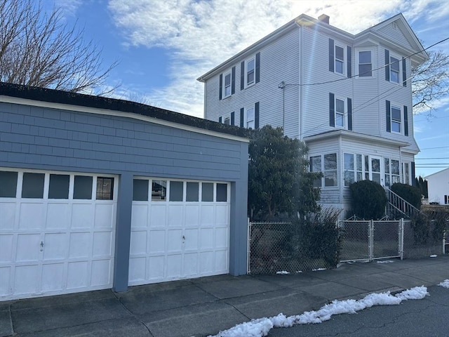 view of property exterior with a garage, a chimney, fence, and an outdoor structure