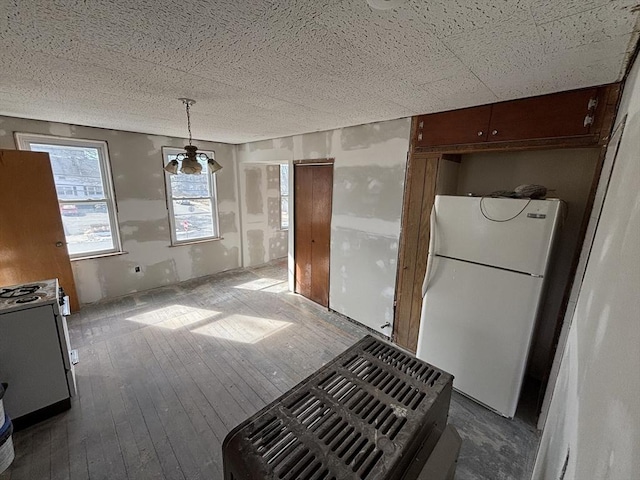 kitchen with hanging light fixtures, wood finished floors, and freestanding refrigerator