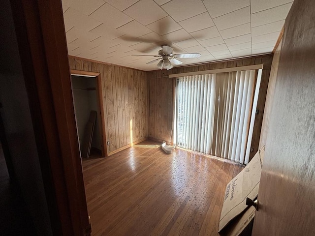 spare room featuring wood finished floors, a ceiling fan, and wooden walls