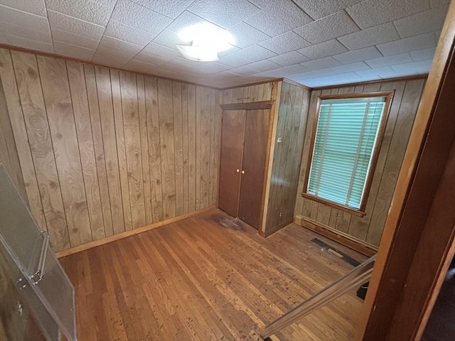 spare room with wood walls, baseboards, and wood finished floors