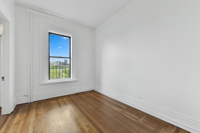 spare room with dark wood-type flooring and baseboards