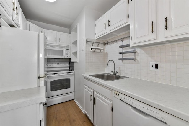 kitchen with white appliances, a sink, backsplash, light countertops, and white cabinetry