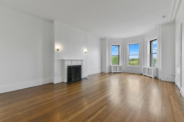 unfurnished living room featuring dark wood finished floors, a fireplace with flush hearth, crown molding, baseboards, and radiator