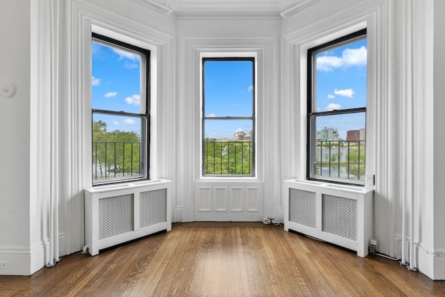 unfurnished room featuring radiator, wood finished floors, and crown molding