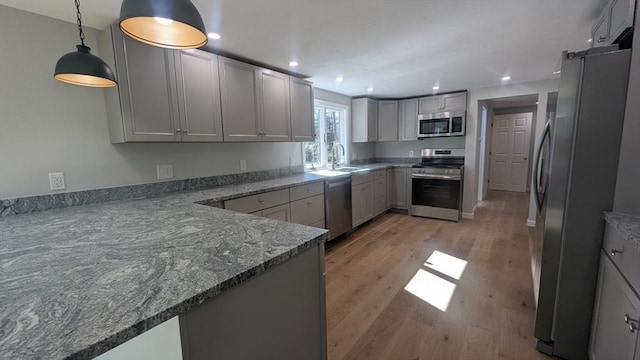 kitchen with decorative light fixtures, recessed lighting, appliances with stainless steel finishes, light wood-style floors, and a sink