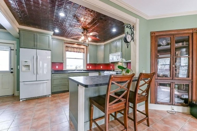 kitchen featuring a kitchen bar, green cabinets, white appliances, ornamental molding, and dark countertops