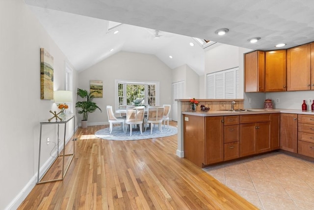 kitchen featuring light wood-type flooring, brown cabinets, a ceiling fan, and light countertops