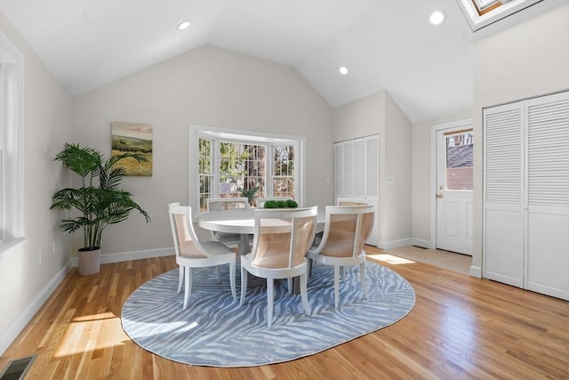 dining room with baseboards, visible vents, vaulted ceiling with skylight, recessed lighting, and light wood-type flooring