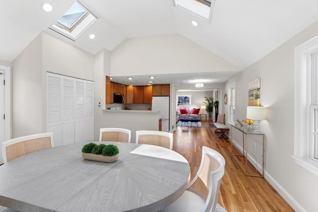 dining room featuring recessed lighting, light wood-type flooring, baseboards, and a skylight