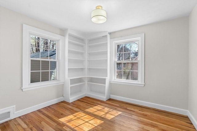 unfurnished room featuring baseboards, visible vents, and a wealth of natural light