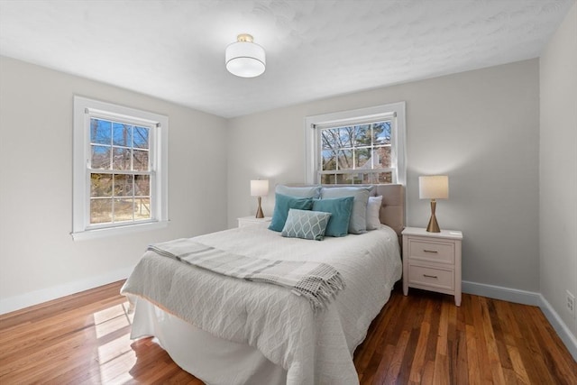 bedroom with multiple windows, wood finished floors, and baseboards