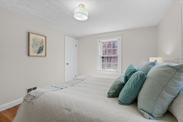 bedroom featuring wood finished floors, visible vents, and baseboards