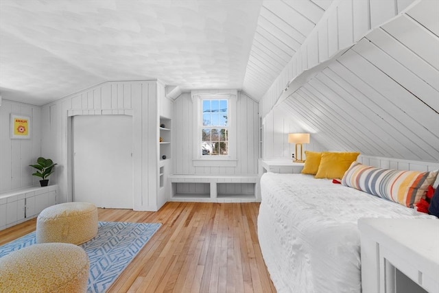 bedroom featuring wooden walls, hardwood / wood-style floors, and vaulted ceiling