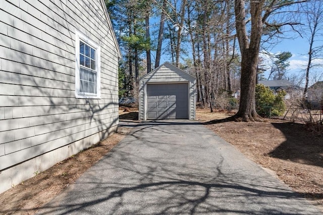 exterior space with aphalt driveway, a detached garage, and an outdoor structure