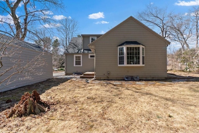 back of house featuring a shingled roof