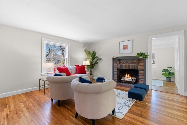 living area with a brick fireplace, light wood-style flooring, and baseboards