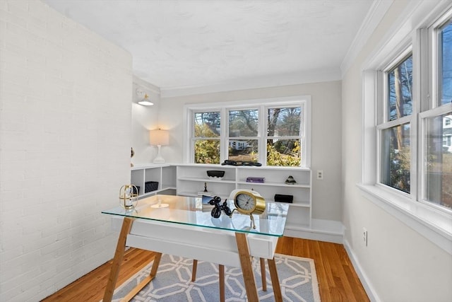 office space featuring ornamental molding, brick wall, baseboards, and wood finished floors