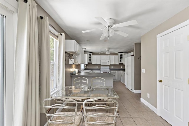 dining room with baseboards, ceiling fan, and light tile patterned flooring