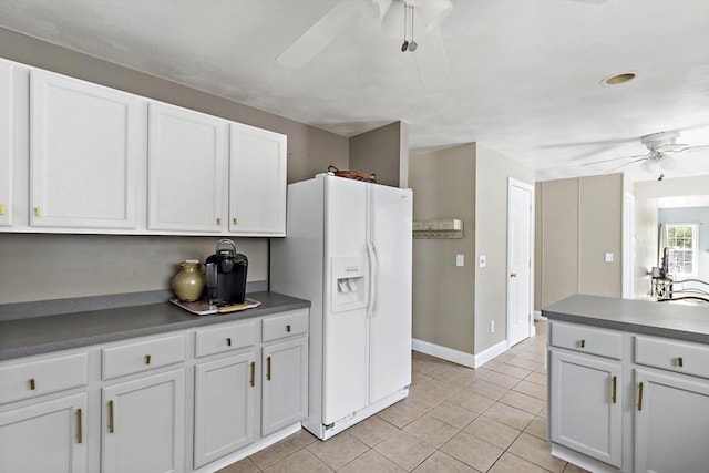 kitchen with a ceiling fan, dark countertops, white refrigerator with ice dispenser, light tile patterned floors, and white cabinets