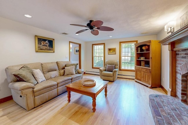 living room with a baseboard heating unit, a fireplace, ceiling fan, light wood finished floors, and recessed lighting