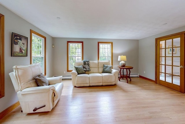 living area with light wood-style flooring, baseboard heating, and baseboards